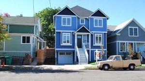 Photo of a blue house, taller than the houses on either side.